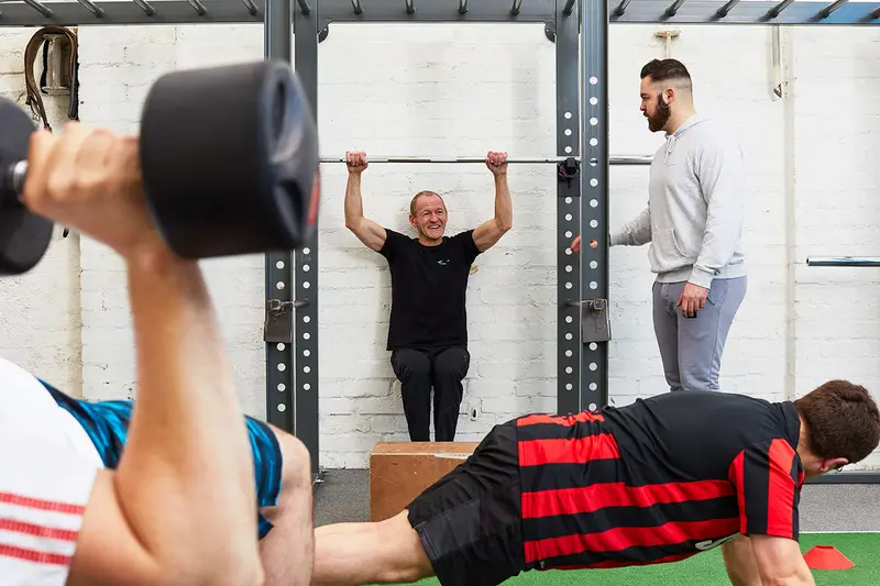A Transformation Fit coach watching a member's wall sit in the Heanor Street studio